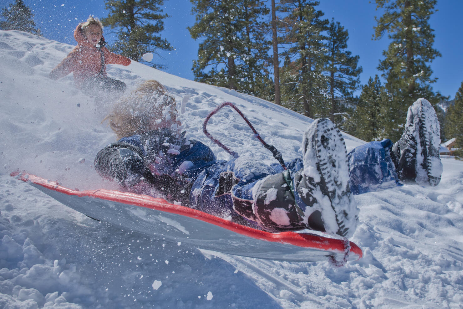small boy on sled crashing through snow