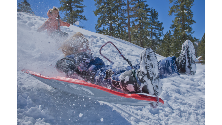 small boy on sled crashing through snow