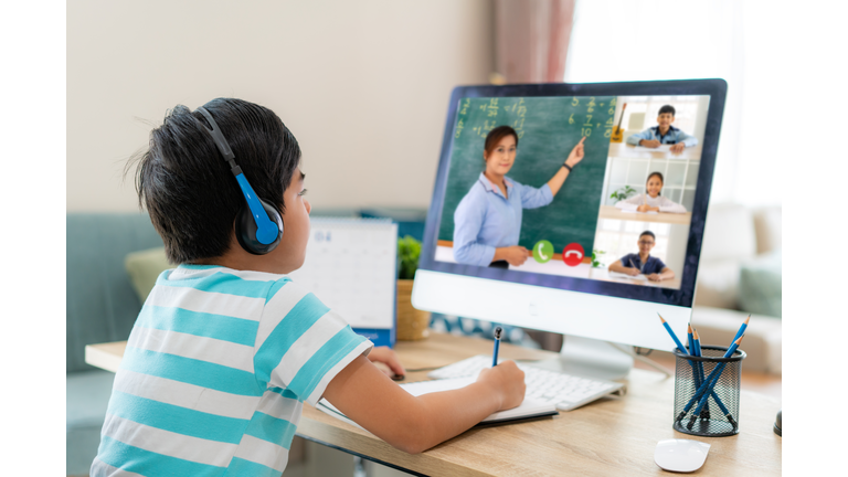 Asian boy student video conference e-learning with teacher and classmates on computer in living room at home. Homeschooling and distance learning ,online ,education and internet.