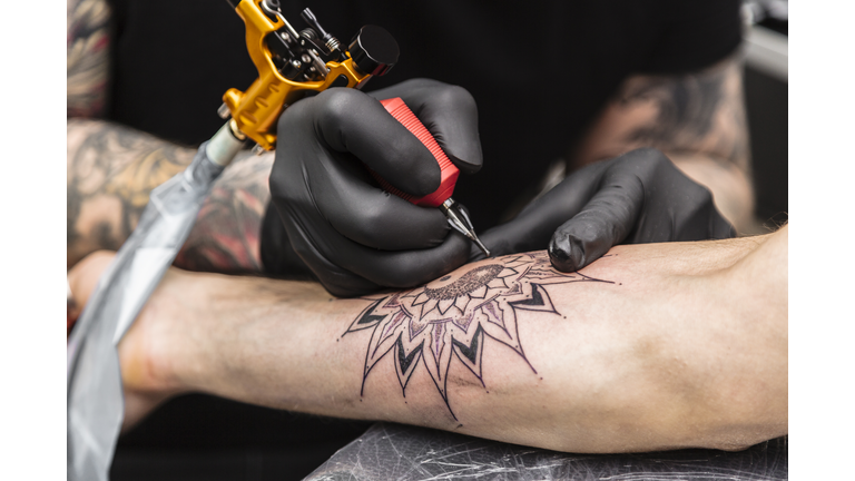 Process of creating tattoo in form of black flower