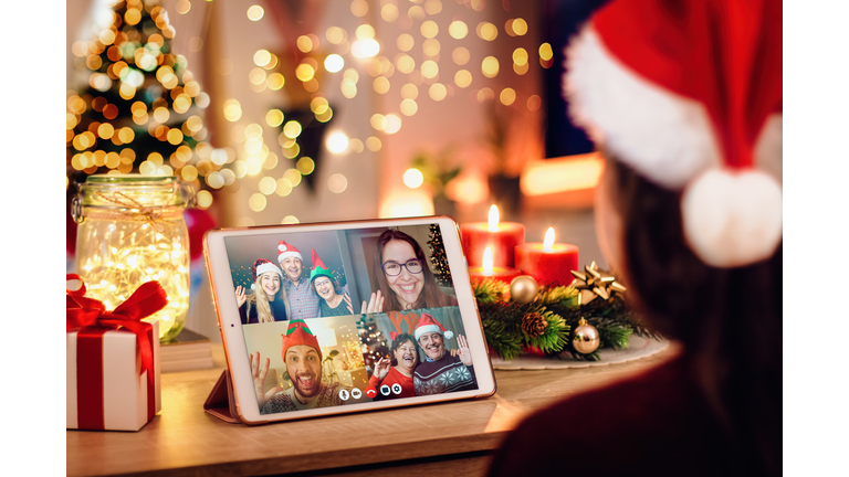 Young woman having a Christmas video call with her happy family. Concept of families in quarantine during Christmas because of the coronavirus. Xmas still life with a tablet in a cozy room