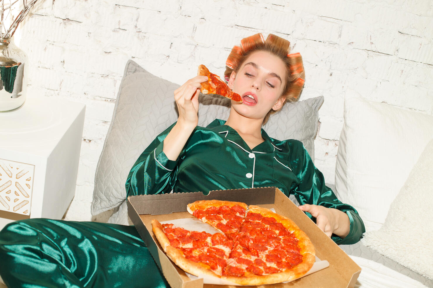 lazy girl in pajamas eating pizza in bedroom