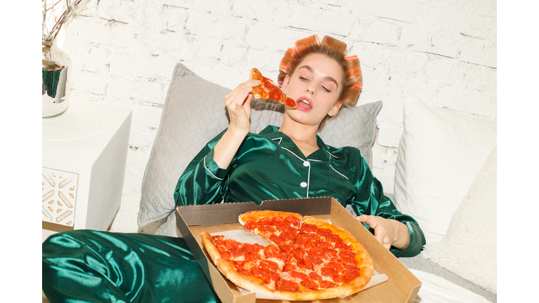 lazy girl in pajamas eating pizza in bedroom