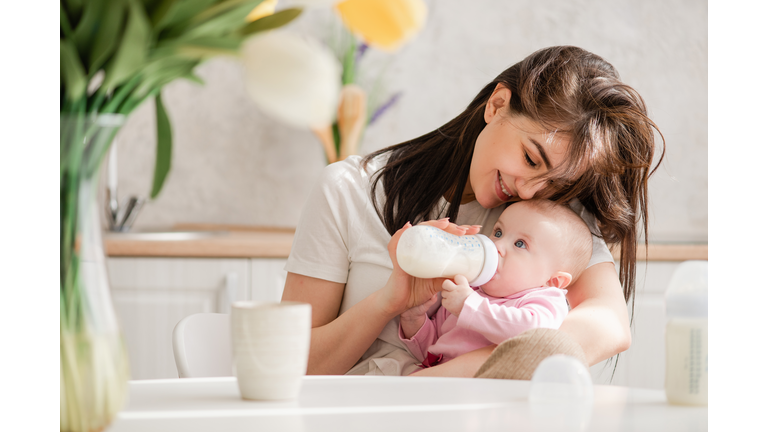 Feeding newborn girl with formula in a bottle.