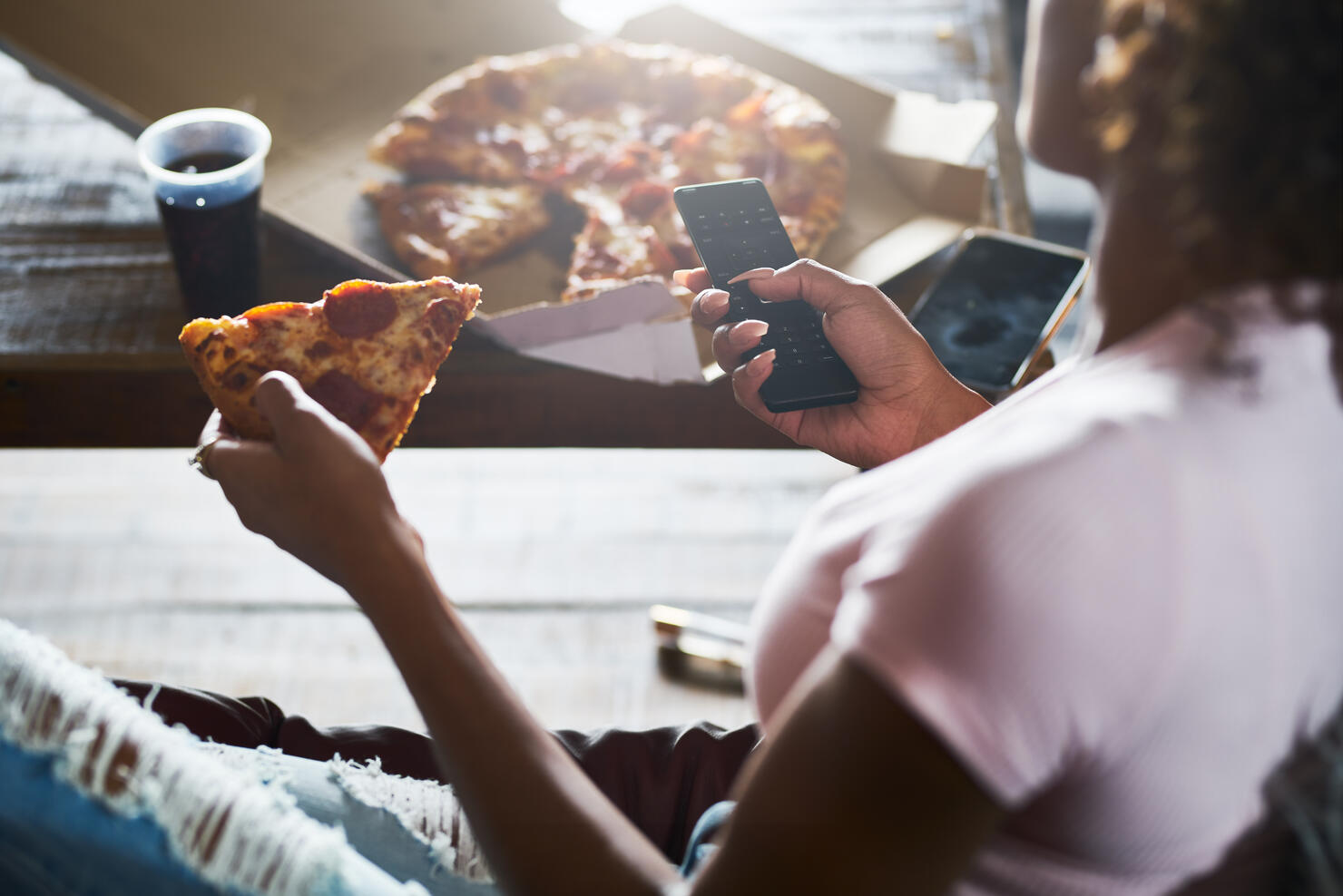 woman unwinding by watching tv and eating pizza