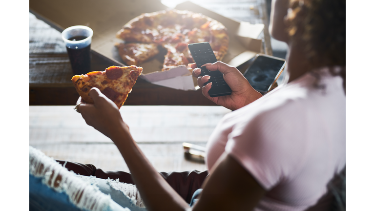 woman unwinding by watching tv and eating pizza