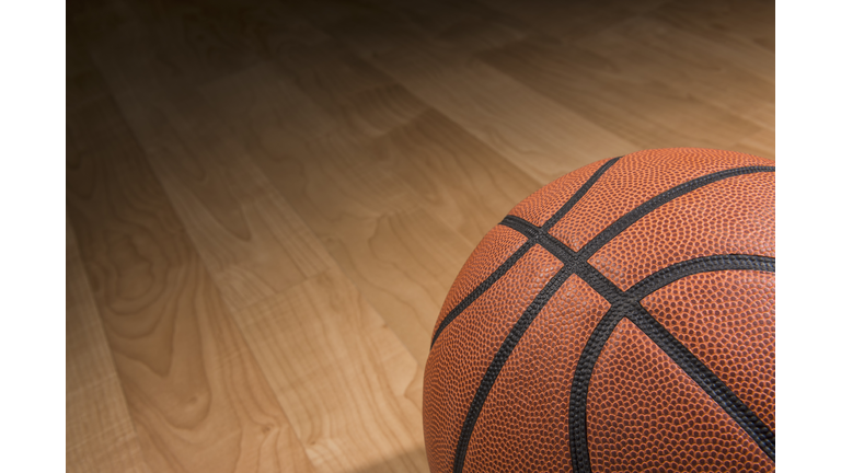 Basketball sitting in the spotlight on a court
