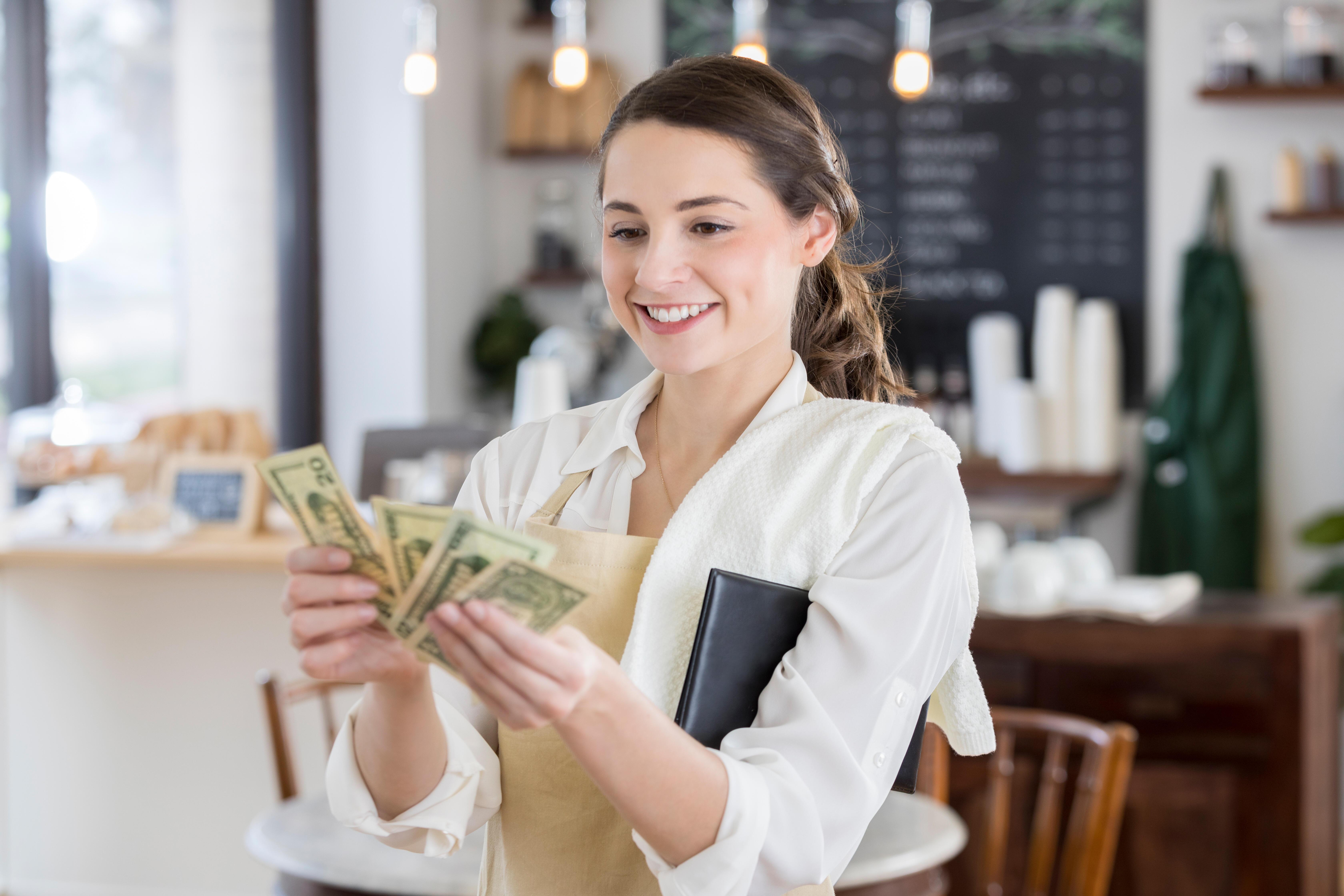 Получение большой. Деньги на девушке кафе. A woman counting Dollars in the House.