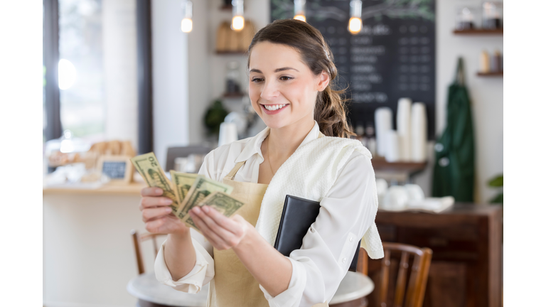 Happy waitress is pleased after receiving a large tip