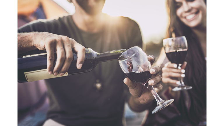 Close up of pouring red wine into a glass outdoors.