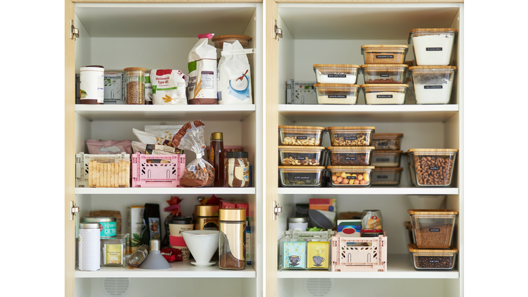 A middle-aged woman tidies up her cupboard in the kitchen and reorganizes everything