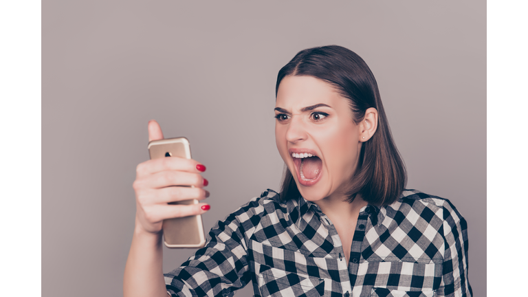 A portrait of an angry young woman disappointed with the news from her work and screaming on the phone