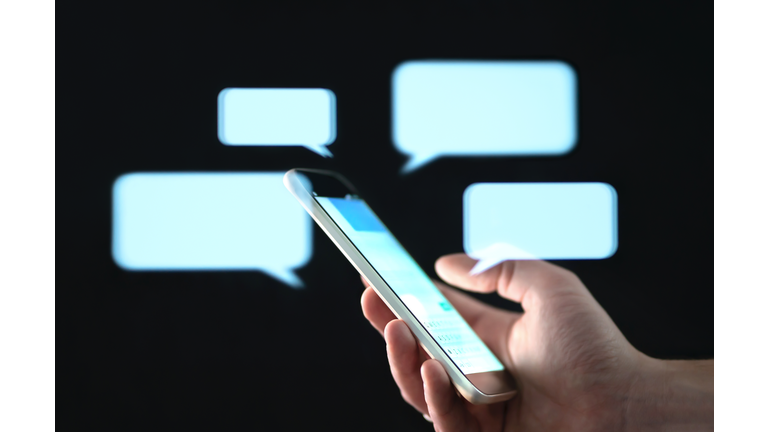 Text messages in cellphone screen with abstract hologram speech bubbles. Instant messaging app. Texting, group chat, sexting or sms concept.