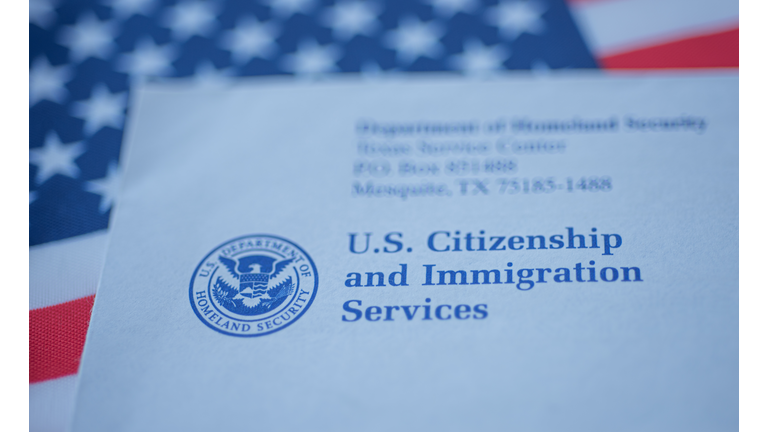 Hand touching Letter (Envelope) from USCIS on  flag of USA background.