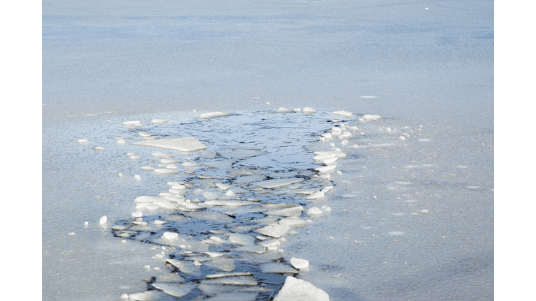 Hole in the thin ice. Someone fell through the ice. Dangerous concept. Freezing and melting time for ice on the water reservoirs in winter.