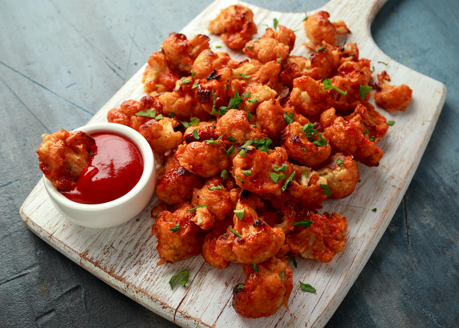Vegan cauliflower buffalo wings on white wooden board
