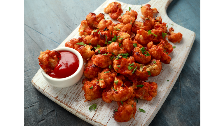 Vegan cauliflower buffalo wings on white wooden board