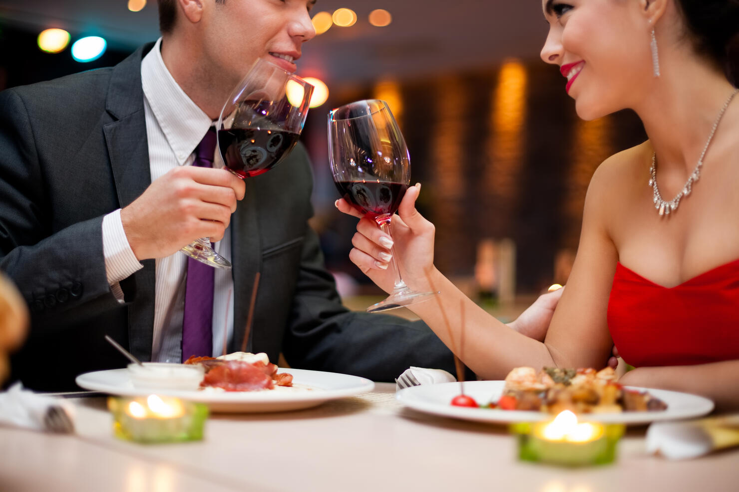A young couple toasting wine glasses at a fancy restaurant