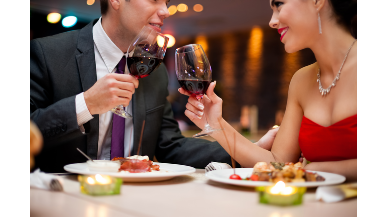 A young couple toasting wine glasses at a fancy restaurant