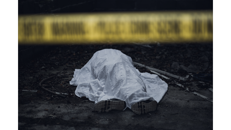 Dead body on the ground behind a cordon tape