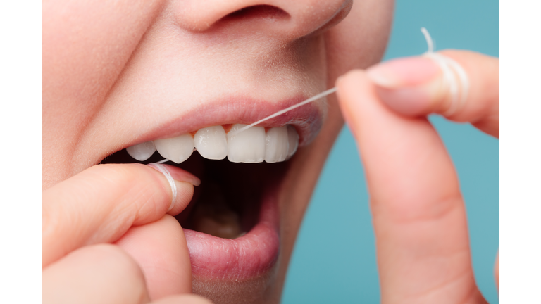 side view woman face smiling with dental floss.