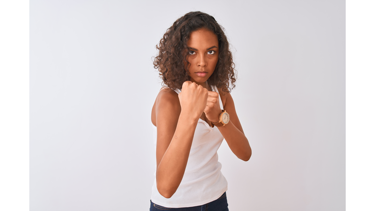 Young brazilian woman wearing casual t-shirt standing over isolated white background Ready to fight with fist defense gesture, angry and upset face, afraid of problem