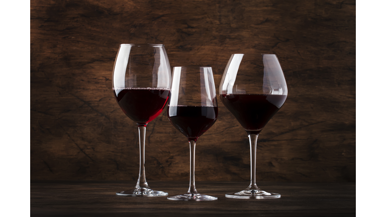 Wine glass. Selection of red wines on wine tasting. Dry, semi-dry, sweet red wine on old wooden table background. Copy space