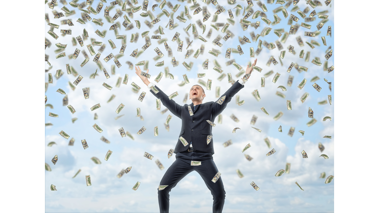 Happy businessman in celebrating pose with loads of money in