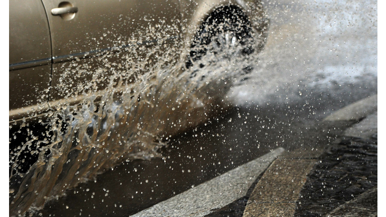 A car drives through a dirty puddle on J