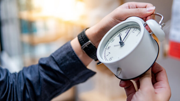 Male hand adjusting the time on white clock
