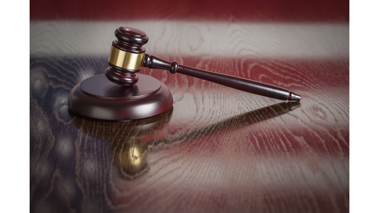 Wooden Gavel Resting on Flag Reflecting Table