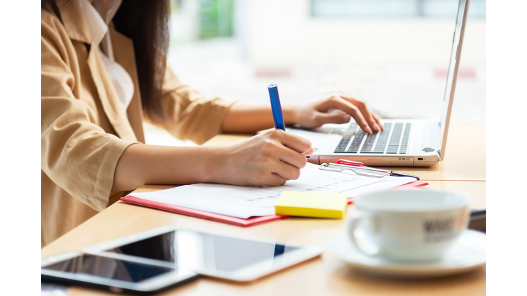 Asian woman using laptop at home while sitting the wooden table.hands typing on the notebook keyboard. Online training education and freelance work. Computer, laptop and studying remotely.