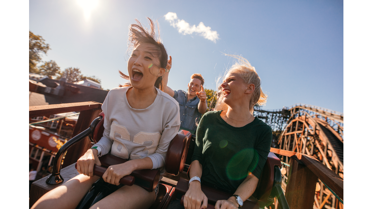 Young friends on thrilling roller coaster ride