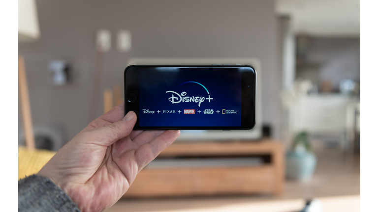 Disney+ startscreen on  mobile phone. Disney+ online video, content streaming subscription service. Man holds his smartphone up and looks at disney plus