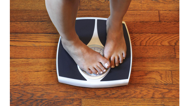 Woman on scale unhappy with her weight