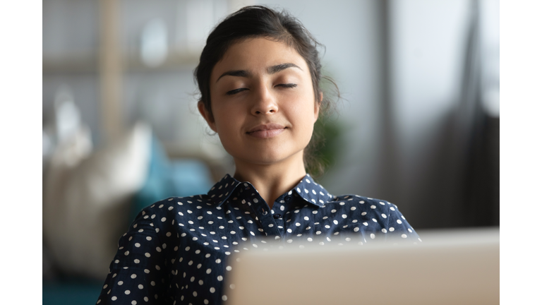 Millennial Indian woman relax at workplace taking nap