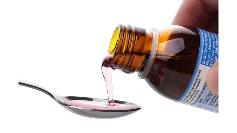 Cough syrup being poured on a spoon