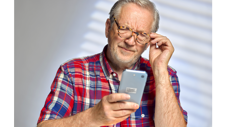 Senior Man staring at his smart phone in confusion