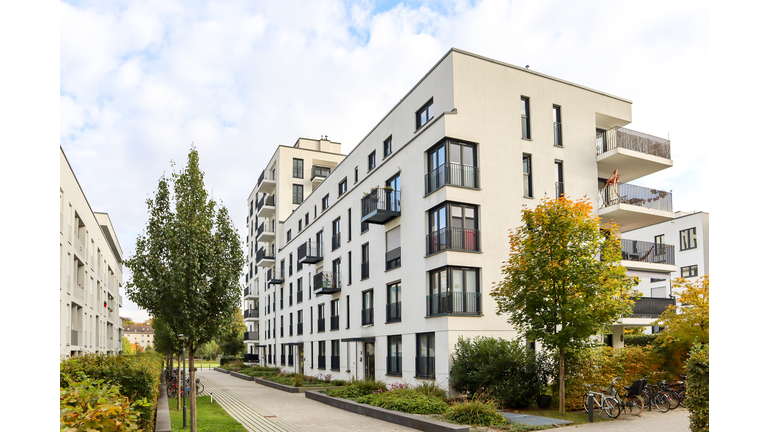 Cityscape with modern residential area, new apartment buildings and green courtyard with pavement and trees in autumn