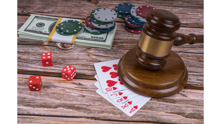 judge gavel and set of playing cards with dices, money and chips, on wooden table.