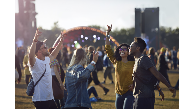 Friends dancing at festival with arms in air