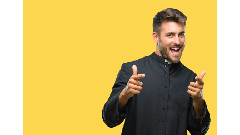 Young catholic christian priest man over isolated background pointing fingers to camera with happy and funny face. Good energy and vibes.