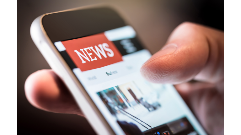 Online news in mobile phone. Close up of smartphone screen. Man reading articles in application. Hand holding smart device. Mockup website.