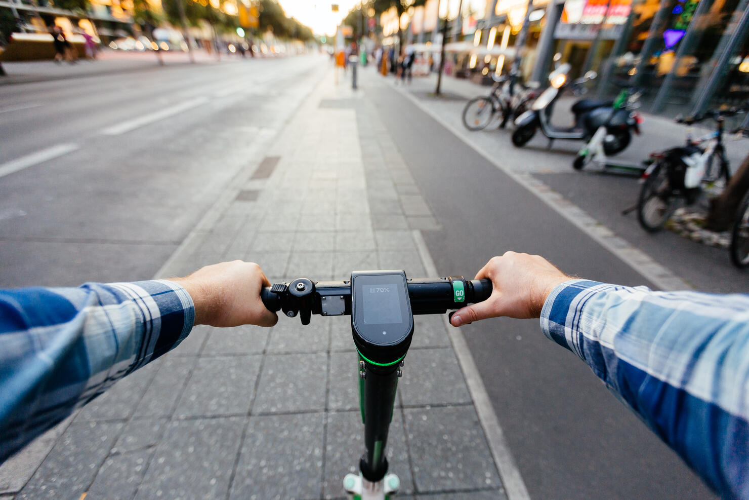 Riding electric scooter in the city, personal perspective view