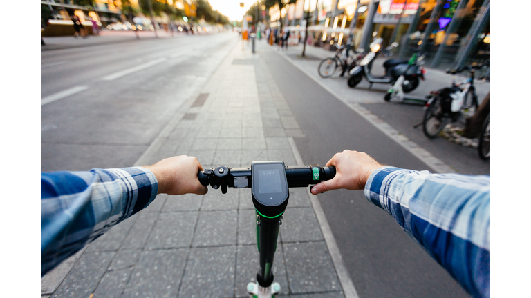 Riding electric scooter in the city, personal perspective view