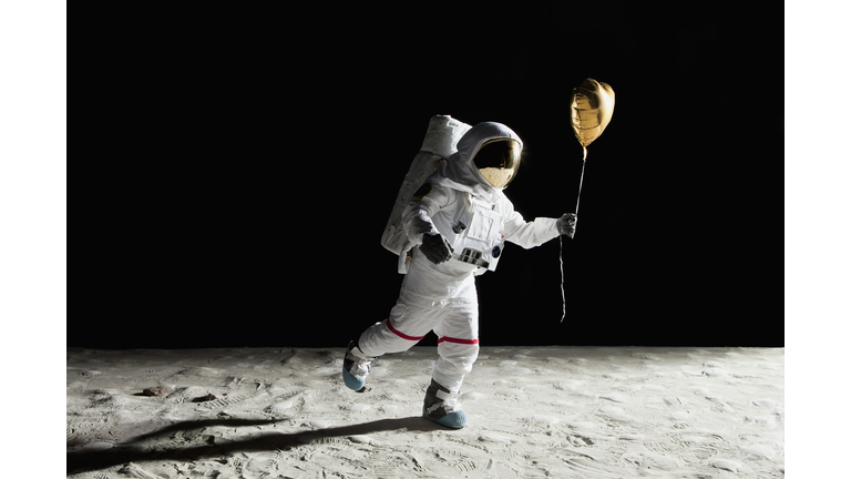 An astronaut on the moon holding a heart shaped helium balloon