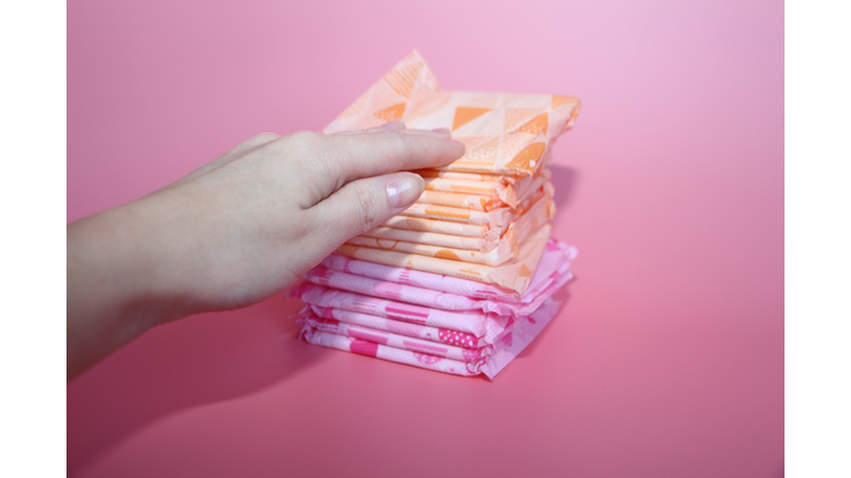 A beautiful female hand rests on several sanitary pads.