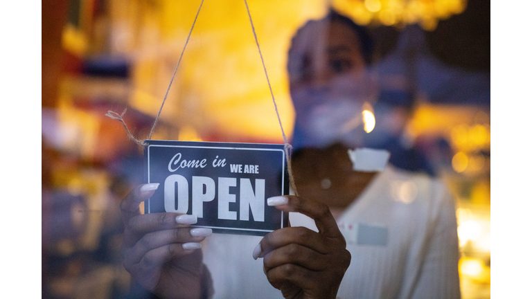 Business owner hanging an open sign at a cafe