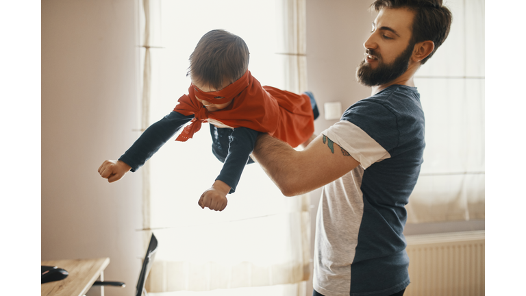 Father playing with his little son dressed up as a superhero