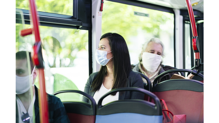 Woman wearing protective mask sitting in bus looking out of window, Spain